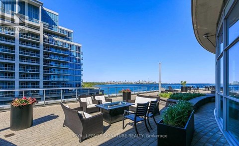 A balcony with chairs and a table overlooking a body of water.
