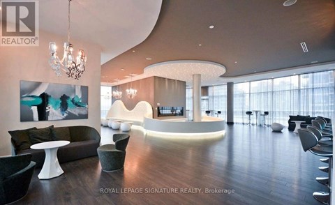 A modern living room with a curved white wall and a chandelier.