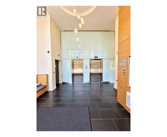 A hallway with a glass door and a bench on the left side.