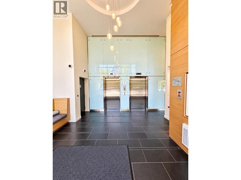A hallway with a glass door and a bench on the left side.
