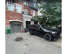 A black car is parked in front of a red brick building.