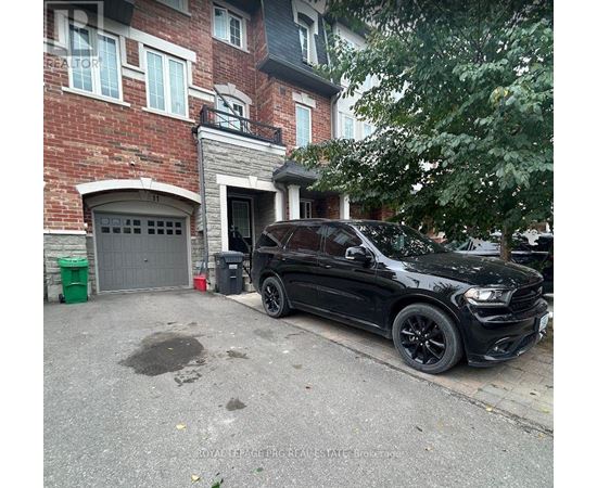 A black car is parked in front of a red brick building.