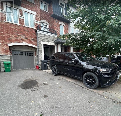 A black car is parked in front of a red brick building.