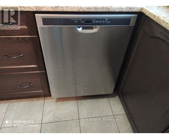 A dishwasher is placed in a kitchen with brown cabinets.