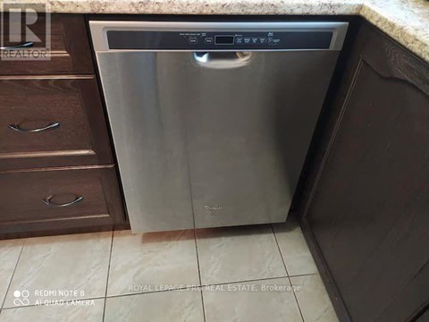 A dishwasher is placed in a kitchen with brown cabinets.