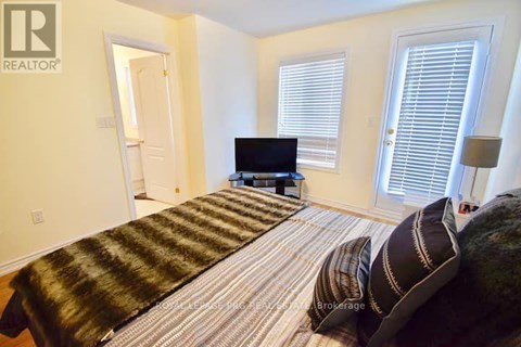 A bedroom with a bed, a television, and a window with blinds.