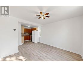A room with a ceiling fan and a refrigerator in it.