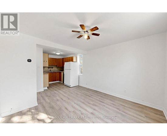 A room with a ceiling fan and a refrigerator in it.