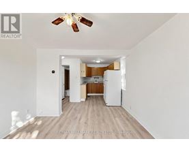 A spacious kitchen with white appliances and wooden floors.