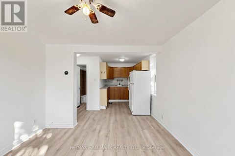 A spacious kitchen with white appliances and wooden floors.
