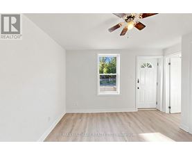 A room with a ceiling fan and a window with a view of trees.