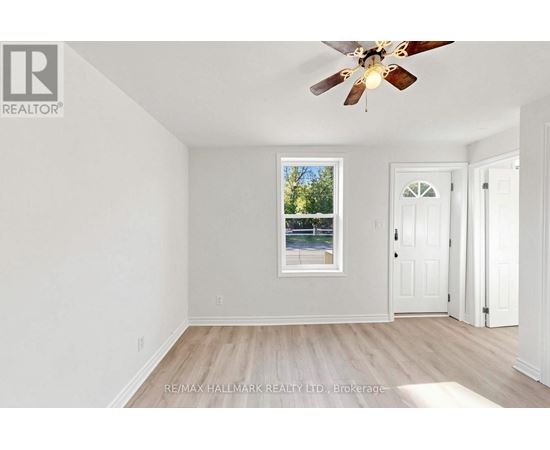 A room with a ceiling fan and a window with a view of trees.