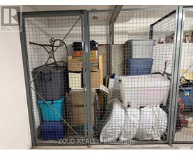 A storage unit is full of various items including a blue container, a white bag, and a black suitcase.