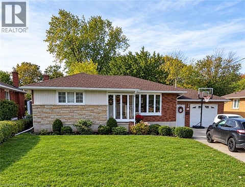 A house with a brown roof and a white garage door is surrounded by green grass.