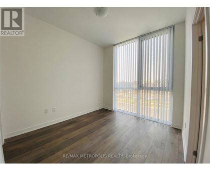 A room with wooden flooring and a window with blinds.