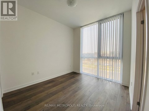 A room with wooden flooring and a window with blinds.