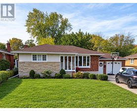 A house with a brown roof and a white garage door is surrounded by a green lawn.