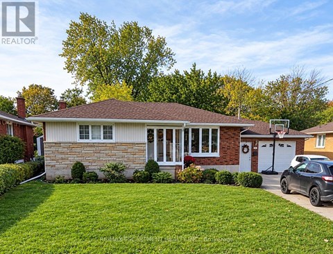 A house with a brown roof and a white garage door is surrounded by a green lawn.
