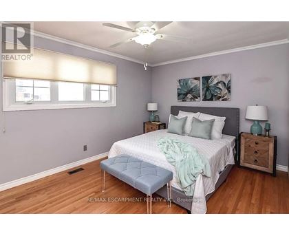A bedroom with a bed, nightstands, and a ceiling fan.