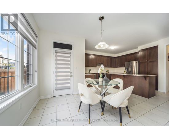 A modern kitchen with white chairs and a glass table.