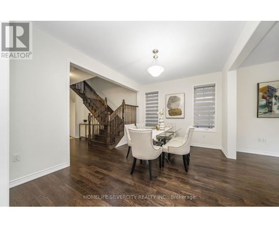 A spacious room with a dining table and chairs and a staircase in the background.