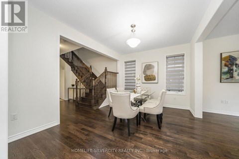 A spacious room with a dining table and chairs and a staircase in the background.