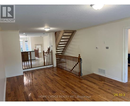 A spacious room with wooden floors and a staircase.