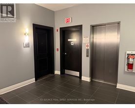 A hallway with a door on the left and a fire extinguisher on the right.
