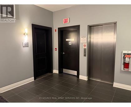 A hallway with a door on the left and a fire extinguisher on the right.