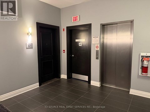 A hallway with a door on the left and a fire extinguisher on the right.