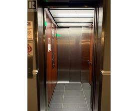 A stainless steel elevator with a sign on the left side.