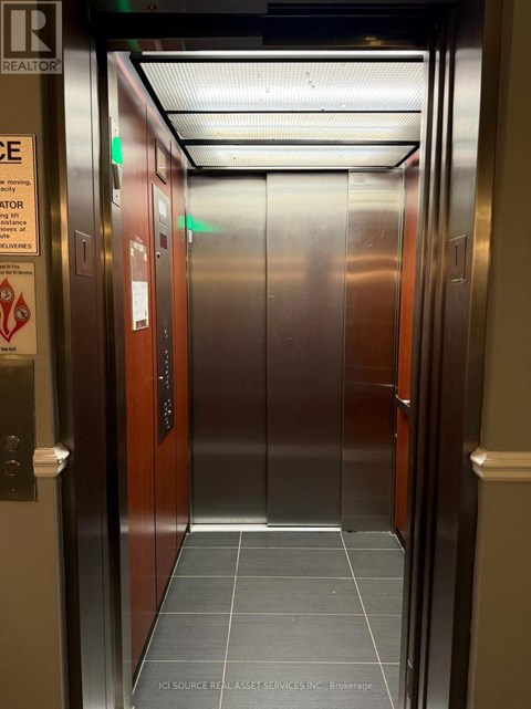 A stainless steel elevator with a sign on the left side.