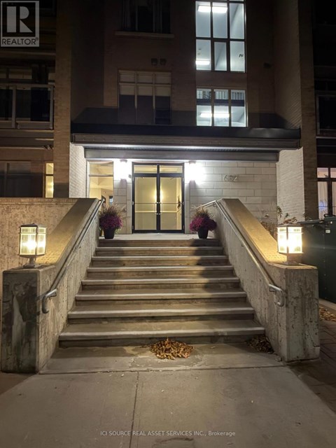 A set of stairs leading to a building entrance with lights on either side.