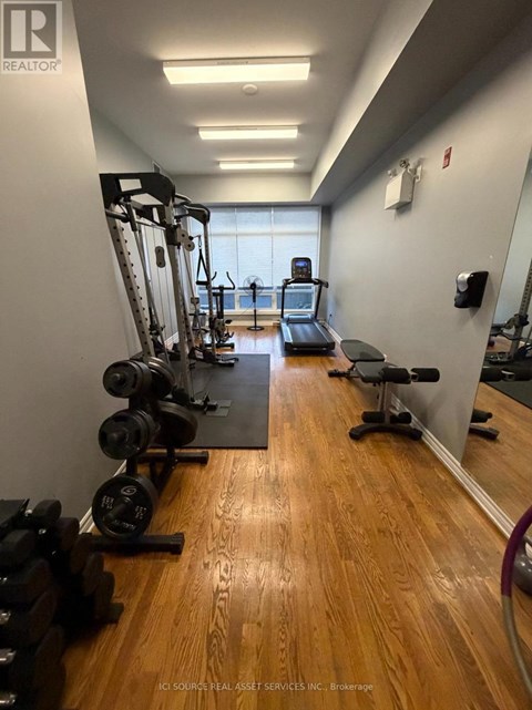 A gym with a mirror, weights, and cardio equipment.
