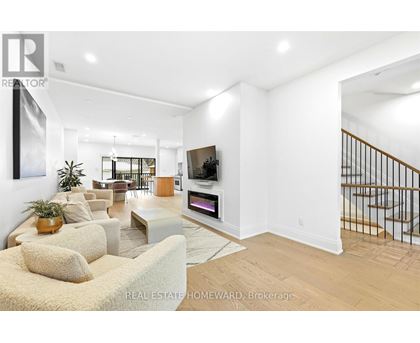 A living room with a couch, a television, and a staircase.