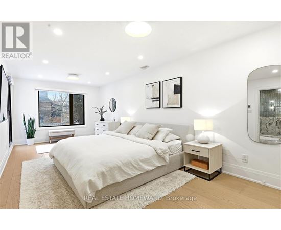 A bedroom with a large bed and a window overlooking a tree-lined street.