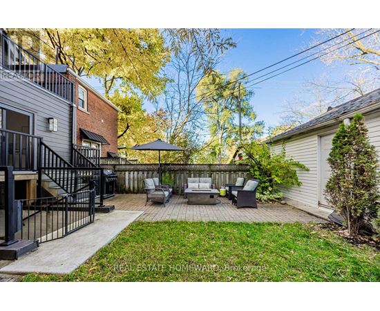 A backyard with a patio, lawn, and trees.