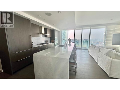 A modern kitchen with dark wood cabinets and a marble countertop.