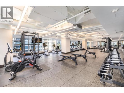 A gym with a variety of equipment including treadmills, weights, and exercise bikes.