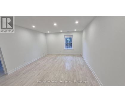 A room with wooden flooring and a window with a view of a building.