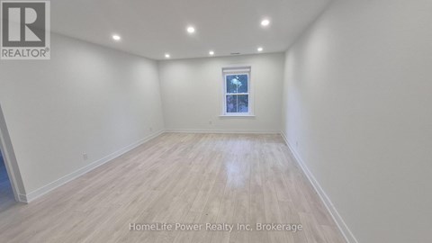 A room with wooden flooring and a window with a view of a building.