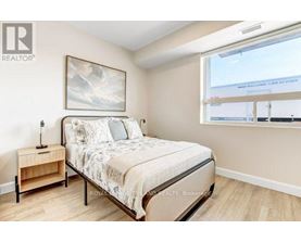 A bedroom with a bed, nightstand, and a painting on the wall.