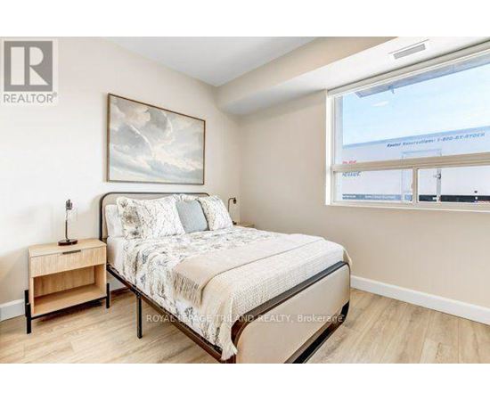 A bedroom with a bed, nightstand, and a painting on the wall.