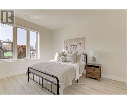 A bedroom with a large bed, a nightstand, and a painting on the wall.