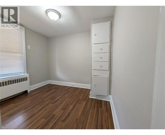 A room with a wooden floor and a white cabinet.