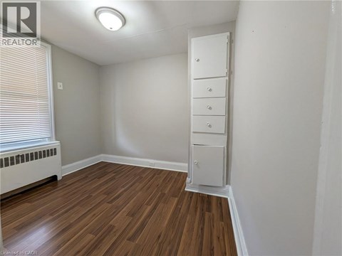 A room with a wooden floor and a white cabinet.