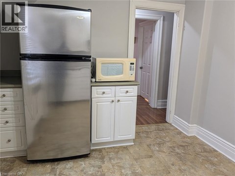 A kitchen with a stainless steel refrigerator and a microwave above a cabinet.