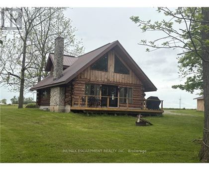 A wooden cabin with a stone chimney is surrounded by a grassy field.