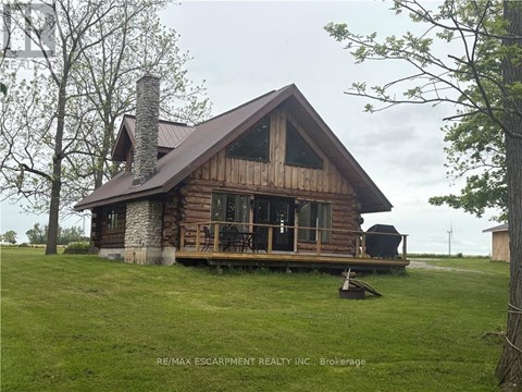 A wooden cabin with a stone chimney is surrounded by a grassy field.
