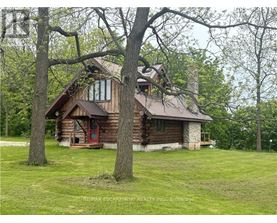 A log cabin sits in a grassy field with trees in the background.
